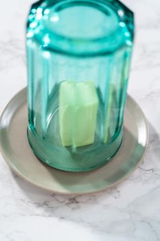 Softening stick of unsalted butter under a hot glass