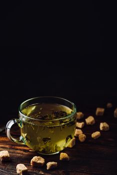 Cup of herbal tea with refined sugar on a wooden background
