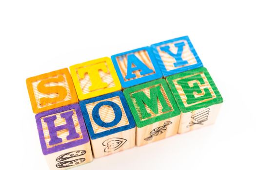 STAY HOME sign out of kids' alphabet blocks on a white background.