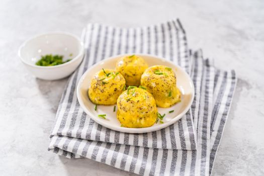 Serving egg bites garnished with fresh chives on a white plate.