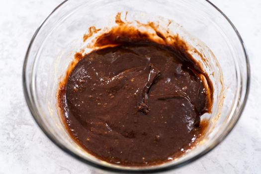 Chocolate cake dough in a glass mixing bowl on the counter.