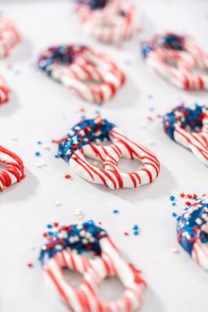 Dipping pretzels twists into melted chocolate to make red, white, and blue chocolate-covered pretzel twists.