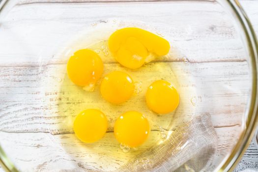 Ingredients in glass mixing bowls to prepare french toast on a wooden table.