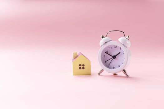 Miniature toy house standing near clock .Dream house,Real estate concept.