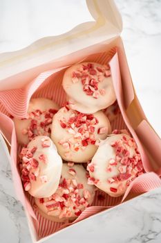 Packing freshly baked peppermint white chocolate cookies into a white paper box.