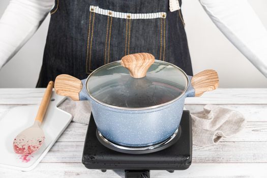 Preparing mixed berry compote from frozen berries in a nonstick cooking pot.