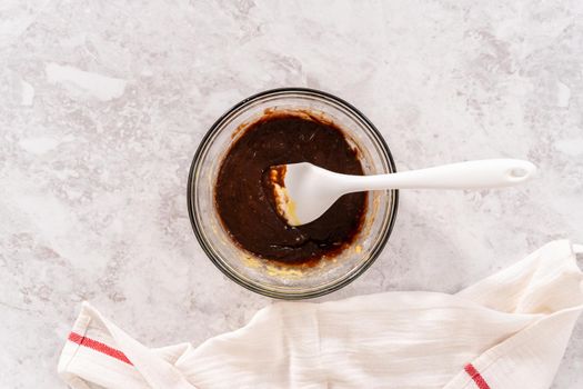 Flat lay. Chocolate cake dough in a glass mixing bowl on the counter.