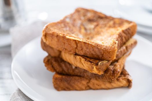 Stack of freshly baked french toast on a white plate.