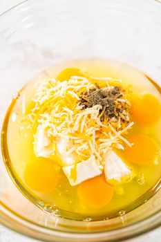 Mixing ingredients with a hand whisk in a glass mixing bowl to make egg bites.