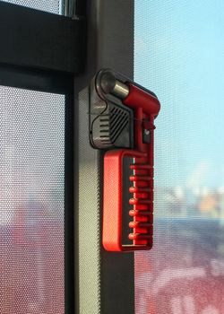 Red hammer, for breaking the window during emergency evacuation, on public bus window.