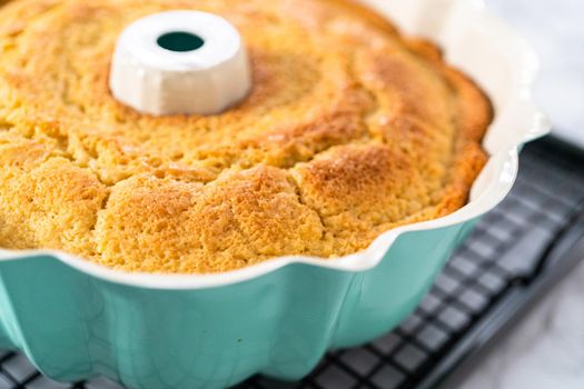 Cooling freshly baked a lemon pound cake on a cooling kitchen rack.