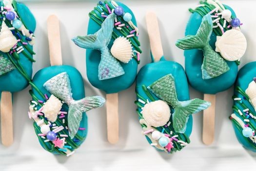 Mermaid cakesicles with drizzled chocolate, chocolate mermaid tails, seashells, and sprinkles.