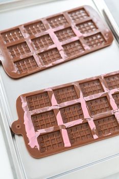 Removing mini pink chocolates from silicone chocolate mold.