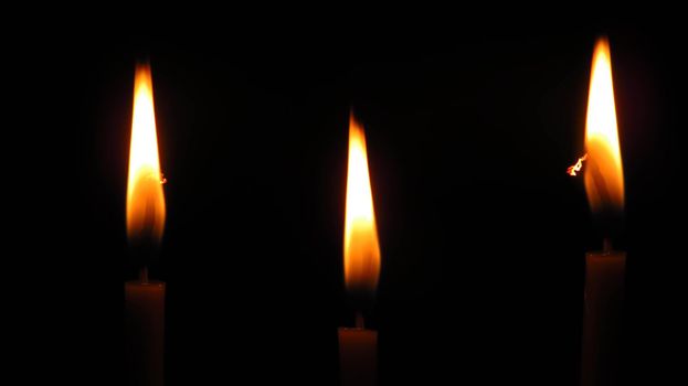 three mysterious church candles on a dark background.