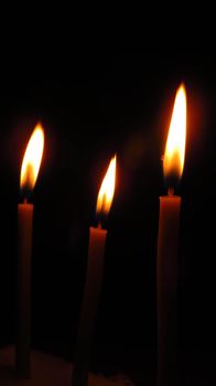 three mysterious church candles on a dark background.