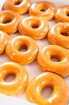 Plain glazed store-bought doughnuts in a white paper box.