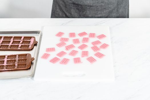 Removing mini pink chocolates from silicone chocolate mold.