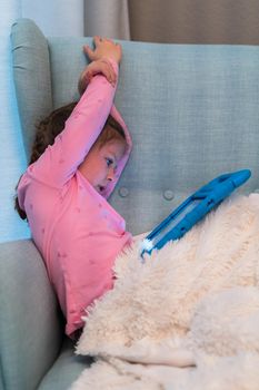 Little girl reading books on her tablet at homeschool.