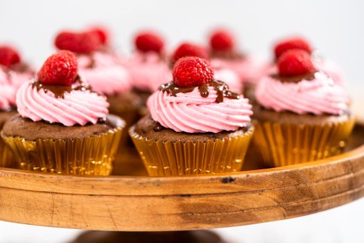 Gourmet chocolate raspberry cupcakes drizzled with chocolate ganache and topped with a fresh raspberry.