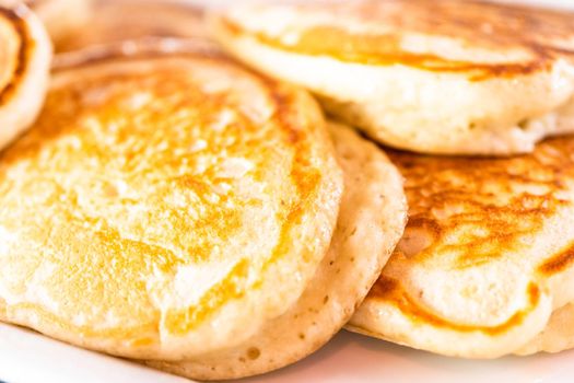 Freshly made pancakes on a white serving plate.