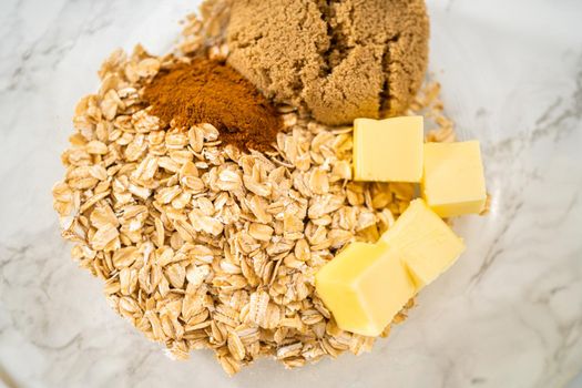 Mixing ingredients in a large glass mixing bowl to bake banana oatmeal muffins.