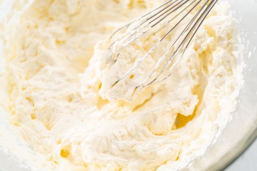 Mixing ingredients in a glass mixing bowl to prepare the homemade whipped cream.