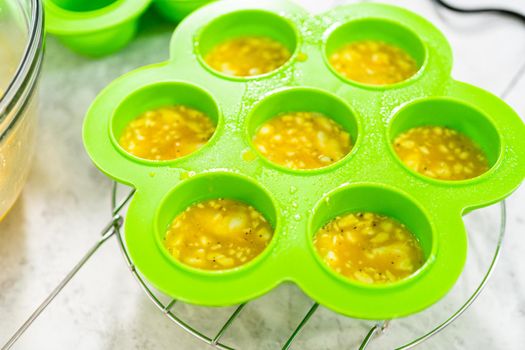 Filling silicone molds with egg mixture to make egg bites in a pressure cooker.