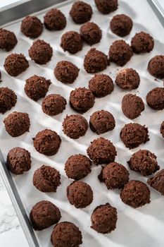 Scooping cookie dough with a small dough scoop into a baking sheet lined with parchment paper to bake peppermint white chocolate cookies.