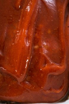 Glazing classic meatloaf with sweet glaze in a loaf pan lined with parchment paper.