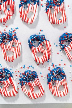 Dipping pretzels twists into melted chocolate to make red, white, and blue chocolate-covered pretzel twists.