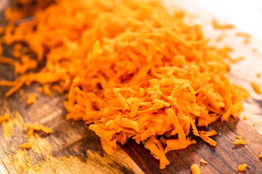 Grated organic orange carrots on a wood cutting board.