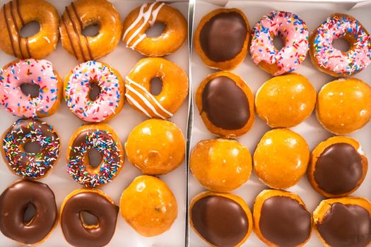 Flat lay. Variety of store-bought doughnuts in a white paper box.