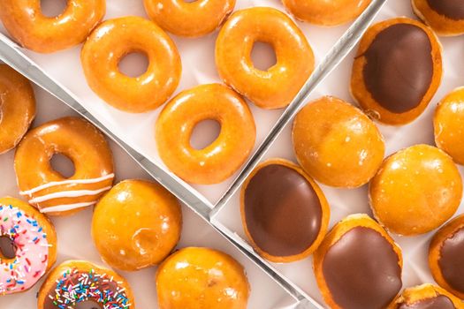 Flat lay. Variety of store-bought doughnuts in a white paper box.