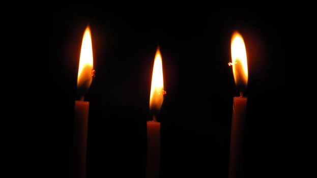 three mysterious church candles on a dark background.