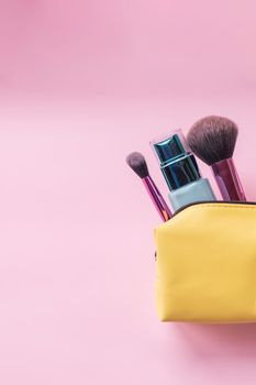 Top view of set of make up and skin care products spilling out of cosmetics bag on blue background. Beauty concept.