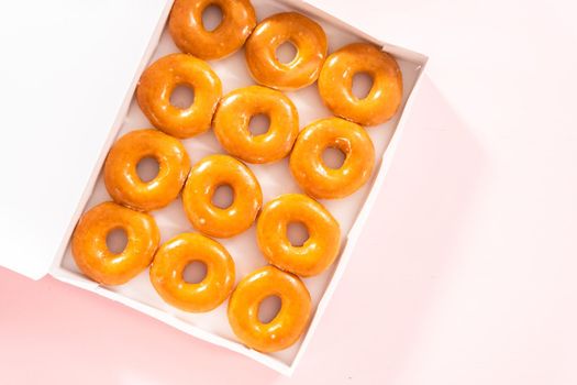 Flat lay. Plain glazed store-bought doughnuts in a white paper box.