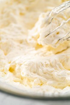 Mixing ingredients in a glass mixing bowl to prepare the homemade whipped cream.