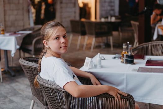 Girl Tourist Resting in the Ancient Narrow Street On A Beautiful Summer Day In MEDITERRANEAN MEDIEVAL CITY, OLD TOWN KOTOR, MONTENEGRO. Young Beautiful Cheerful Woman Walking On Old Street