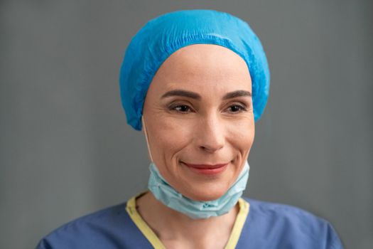 Female Medic Smiles Taking Off Her Protective Mask, Young Nurse Is Happy To End The Coronavirus Epidemic, Caucasian Woman On Grey Background, Quarantine Concept