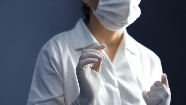 Female doctor in disposable white gloves. Selective focus on woman's hands in foreground. Close up shot. Toned image.