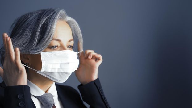 Pretty gray-haired business woman correct mask on her face. Empty space for text at right side. Close up portrait. Quarantine concept.