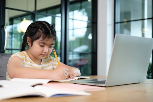 Cute and happy little girl children using laptop computer, studying through online e-learning system.