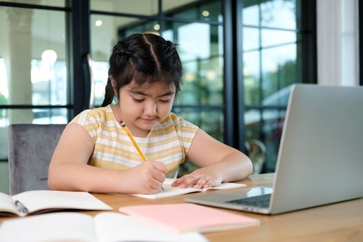 Cute and happy little girl children using laptop computer, studying through online e-learning system.