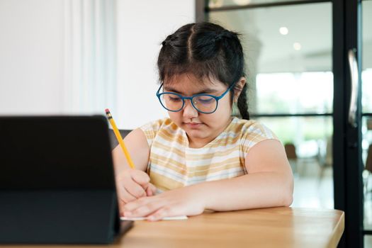 Cute and happy little girl children using laptop computer, studying through online e-learning system.