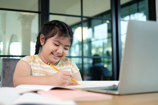 Cute and happy little girl children using laptop computer, studying through online e-learning system.