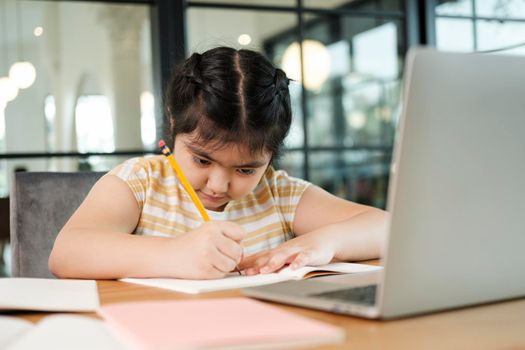 Cute and happy little girl children using laptop computer, studying through online e-learning system.