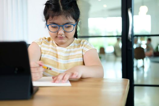 Cute and happy little girl children using laptop computer, studying through online e-learning system.