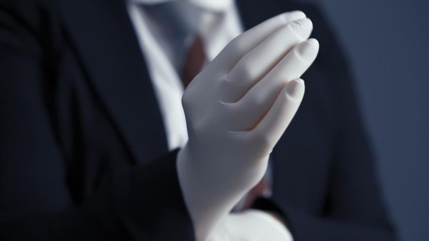 Business person puts on white disposable gloves. Business during and after quarantine. Close up shot.