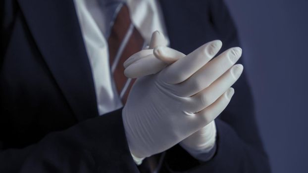 Businesswoman in protective latex gloves and business clothes. Selective focus on female arms correcting her gloves in foreground. Close up shot. Pandemic concept. Tinted image.
