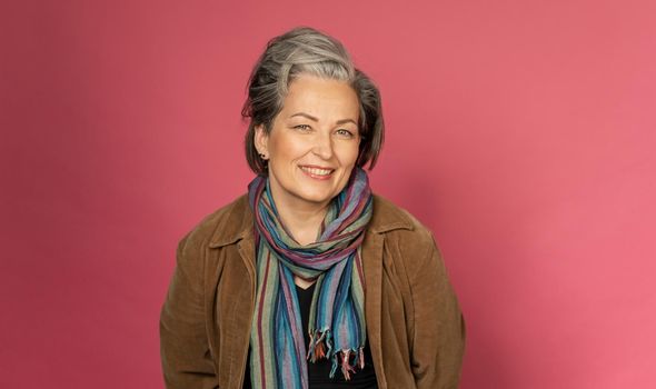 Happy gray-haired woman smiles broadly sexy posing in studio on pink background. Good-looking mature lady with nature make-up. Beauty concept. Vogue concept.